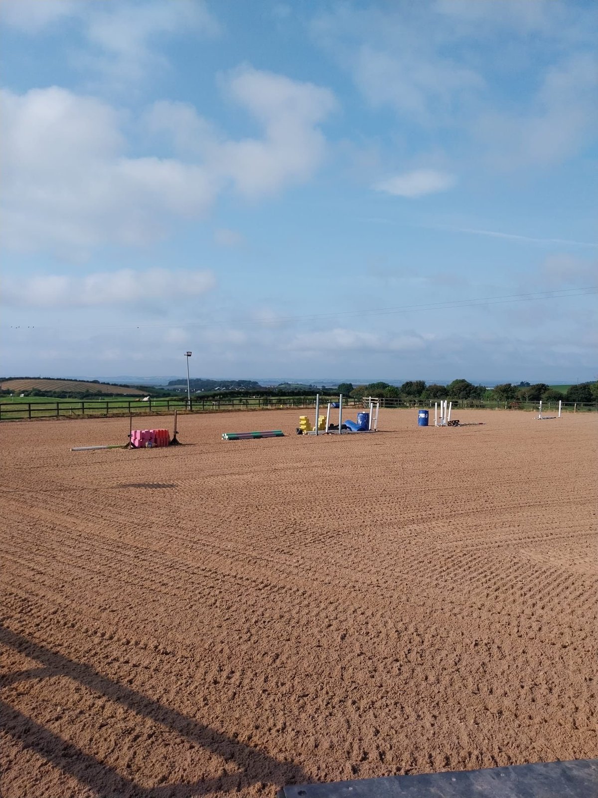 Empty equestrian arena with horse jump obstacles under blue sky with clouds